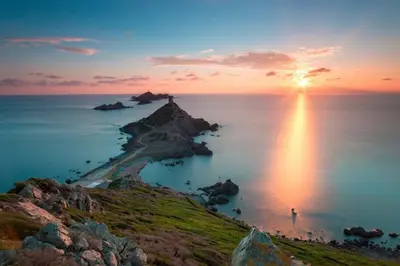 a sunset over a small island in the ocean at STUDIO rue pietonne Ajaccio in Ajaccio
