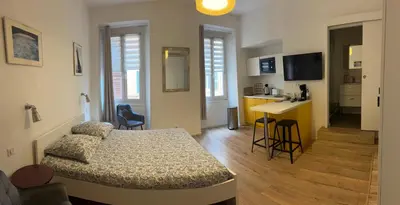a bedroom with a bed and a kitchen with a counter at STUDIO rue pietonne Ajaccio in Ajaccio