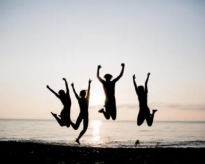 a group of people jumping on the beach at Domaine Naturiste de Riva Bella in Linguizzetta