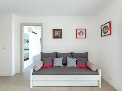 a white bedroom with two beds and a chair at Apartment Bastion-17 by Interhome in Porto-Vecchio