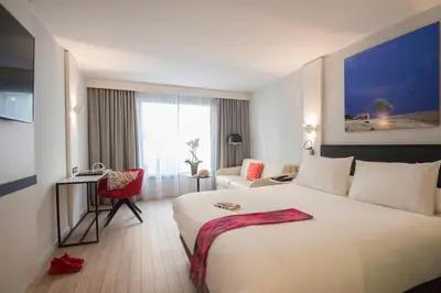 a hotel room with a large bed and a chair at Mercure Ajaccio in Ajaccio