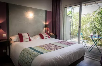a bedroom with a bed and a large window at Golfe Hôtel & Spa Porto-Vecchio in Porto-Vecchio