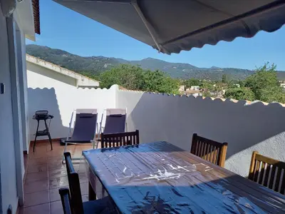 a table and chairs on a balcony with a view at Appartement avec piscine vue mer et montagne in San-Nicolao