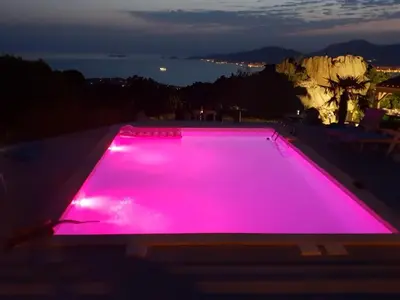 a swimming pool with pink lights on top of a house at Le rocher in Porticcio