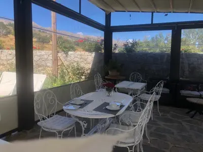 a patio with tables and white chairs and a window at L'Acqua Viva in Calacuccia