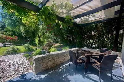 a patio with a table and chairs and a stone wall at Poisson Rouge in Bonifacio