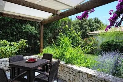 a patio with a table and chairs and a stone wall at Poisson Rouge in Bonifacio