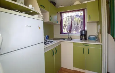a kitchen with green and white cabinets and a refrigerator at Nice Stacaravan In Casalabriva in Casalabriva