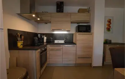a small kitchen with wooden cabinets and a microwave at Amazing Apartment In Moriani Plage in Moriani Plage