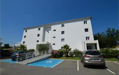 a large white building with cars parked in a parking lot at Amazing Apartment In Moriani Plage in Moriani Plage