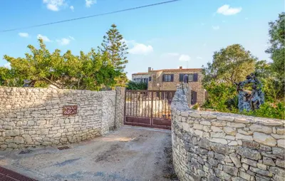 a stone wall with a gate in front of a house at Pet Friendly Apartment in Pianottoli-Caldarello