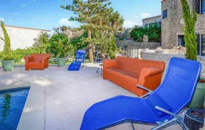 a patio with orange and blue chairs and a pool at Pet Friendly Apartment in Pianottoli-Caldarello