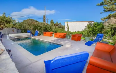 a swimming pool with orange chairs and a swimming pool at Pet Friendly Apartment in Pianottoli-Caldarello