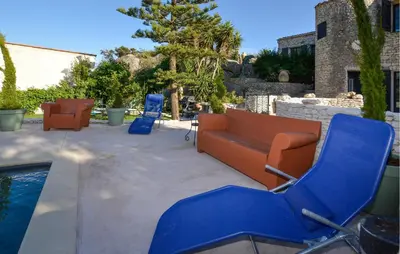 a patio with blue and orange chairs and a pool at Pet Friendly Apartment in Pianottoli-Caldarello