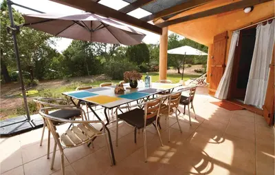 a table with chairs and an umbrella on a patio at Beautiful Home In Porto Vecchio in Porto-Vecchio