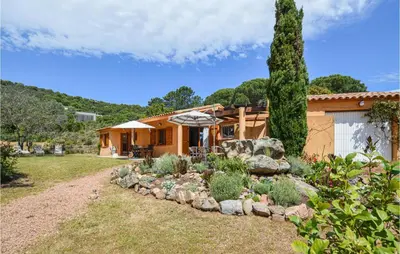 a garden in front of a house with an umbrella at Beautiful Home In Porto Vecchio in Porto-Vecchio