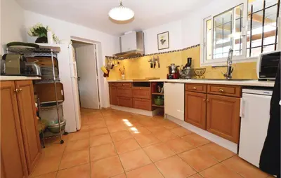 a kitchen with wooden cabinets and a tile floor at Beautiful Home In Porto Vecchio in Porto-Vecchio