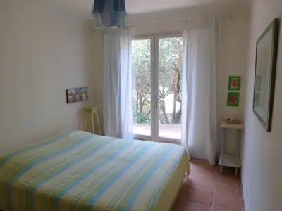 a bedroom with a bed and a large window at CAEDA in Porto-Vecchio