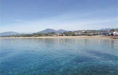 a body of water with a beach and mountains in the background at Gorgeous Apartment In Ajaccio With Wifi in Ajaccio