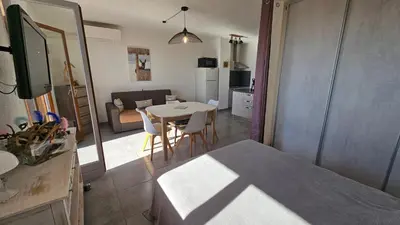 a room with a table and chairs and a living room at Cardellini 10- vue mer-piscine en résidence in Sari Solenzara