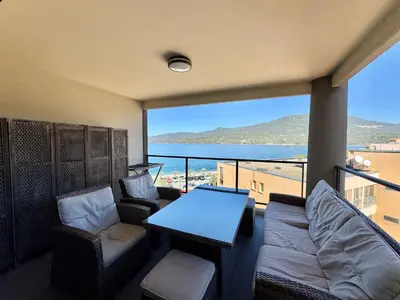 a balcony with a table and chairs and a view of the ocean at Appartement neuf tout confort en bord de mer in Propriano