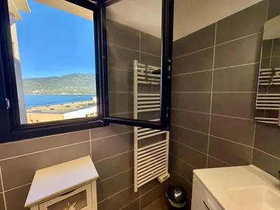 a bathroom with a window with a view of the beach at Appartement neuf tout confort en bord de mer in Propriano