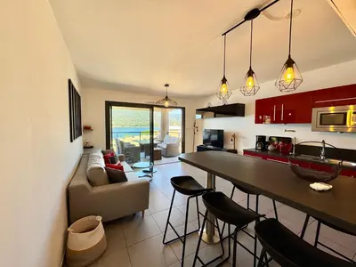 a kitchen and living room with a table and chairs at Appartement neuf tout confort en bord de mer in Propriano
