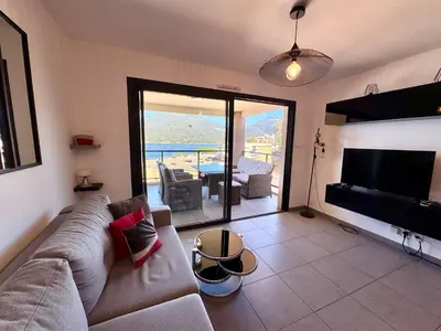 a living room with a couch and a flat screen tv at Appartement neuf tout confort en bord de mer in Propriano