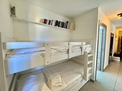 a bedroom with white bunk beds in a room at Appartement neuf tout confort en bord de mer in Propriano