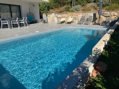 a blue swimming pool with chairs and a table at Villa Mamago in Cirendinu