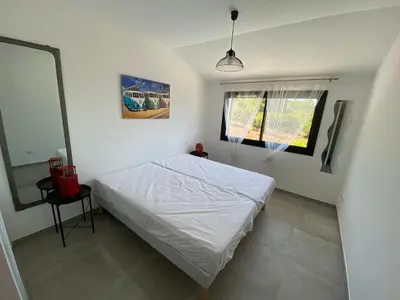 a bedroom with a white bed and a mirror at Villa Mamago in Cirendinu