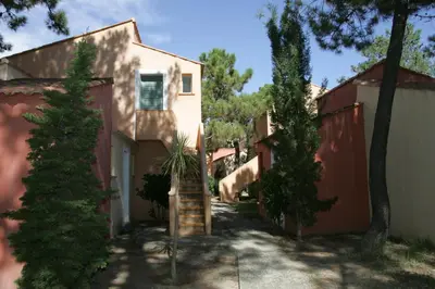 a house with a staircase in a yard with trees at Résidence Cala Bianca in Borgo