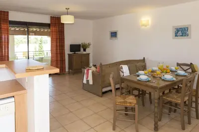 a kitchen and dining room with a table and chairs at Résidence Odalys Les Hameaux de Capra Scorsa in Belgodère