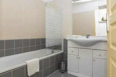 a bathroom with a sink and a bath tub and a mirror at Résidence Odalys Les Hameaux de Capra Scorsa in Belgodère