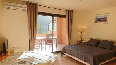 a room with a table and a bed and a television at Résidence A Barcella in Porto Ota