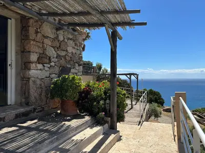 a stone house with flowers on a balcony at CAROLE F3 in Sainte-Lucie de Porto-Vecchio
