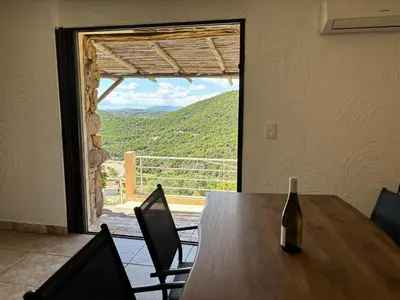 a bottle of wine on a wooden table with a view at CAROLE F3 in Sainte-Lucie de Porto-Vecchio