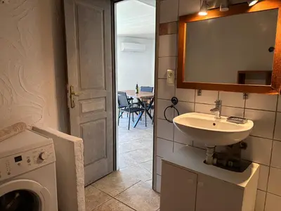 a bathroom with a sink and a washing machine at CAROLE F3 in Sainte-Lucie de Porto-Vecchio