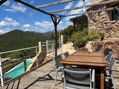 a wooden table and chairs on a deck with a view at CAROLE F3 in Sainte-Lucie de Porto-Vecchio