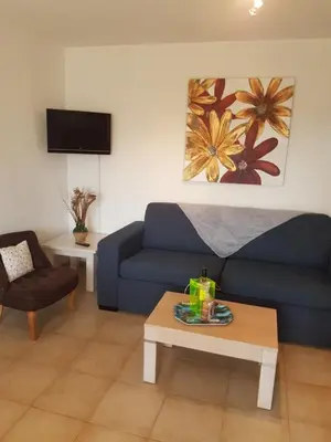 a living room with a blue couch and a table at Domaine de Mélody in Moriani Plage