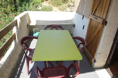 a green table and chairs on a balcony at Suarella in Propriano