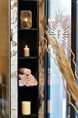 a room with a shelf with towels and a candle at Hôtel Fesch & Spa in Ajaccio