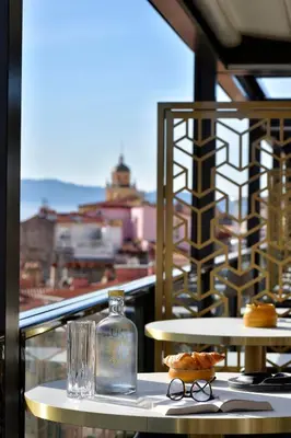 a bottle and glasses sitting on a table on a balcony at Hôtel Fesch & Spa in Ajaccio