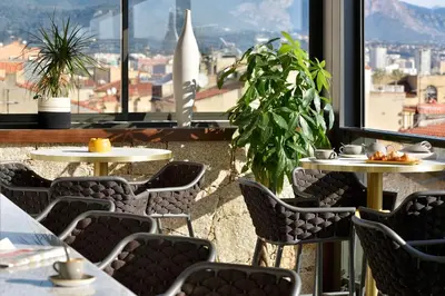 a restaurant with tables and chairs and a view of the city at Hôtel Fesch & Spa in Ajaccio