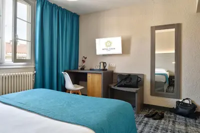 a hotel room with a bed and a desk and a mirror at Hôtel Fesch & Spa in Ajaccio