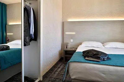 a hotel room with a bed and a bag on the bed at Hôtel Fesch & Spa in Ajaccio