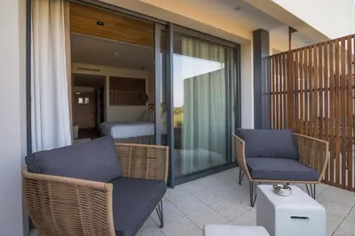 a balcony with a couch and chairs and a bedroom at Golden Tulip Porto-Vecchio in Porto-Vecchio