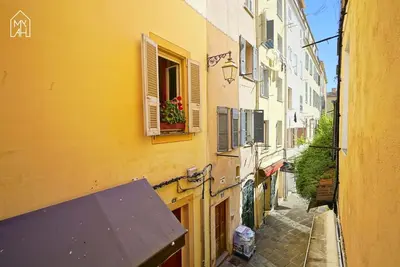 an alley with a yellow building with a window at Carlota - Appartement rénové au cœur de la vieille ville - by TGB in Ajaccio