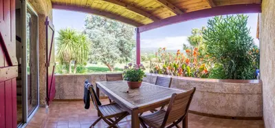 a patio with a table and chairs and a large window at Résidence Marina di Capitello in Porticcio