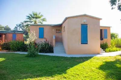 a house with blue shutters in a yard at Résidence Marina di Capitello in Porticcio